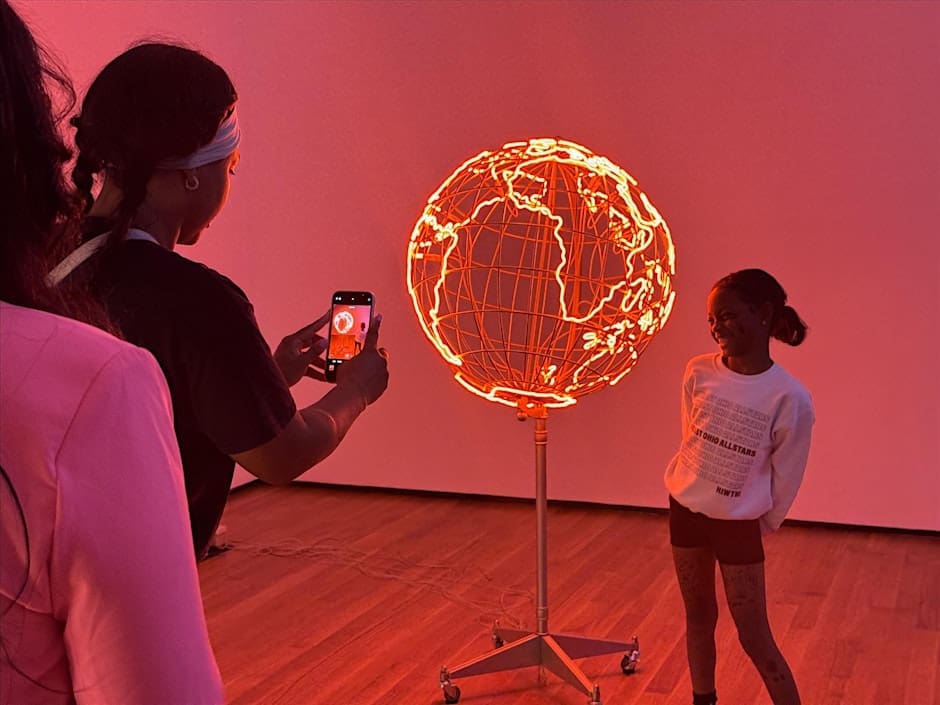 A young girl getting her pictures taken by an artwork.