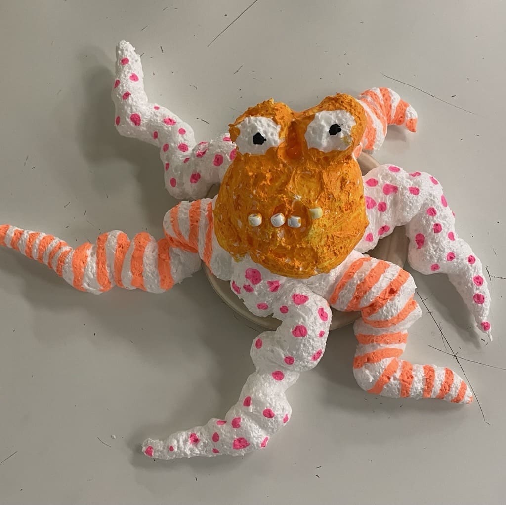 A foam sculpture of a cute little orange creature.