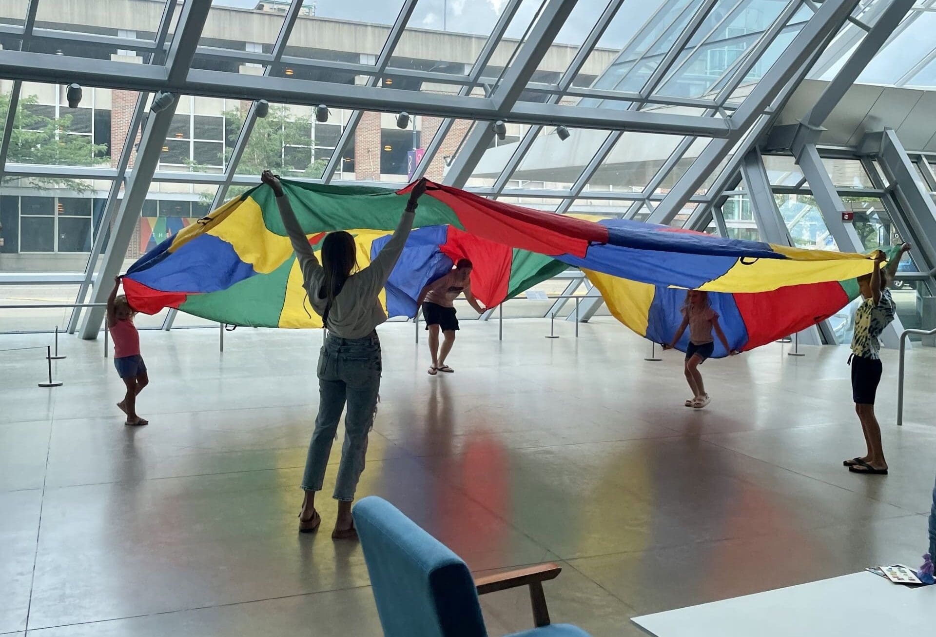Children playing with a large piece of rainbow fabric