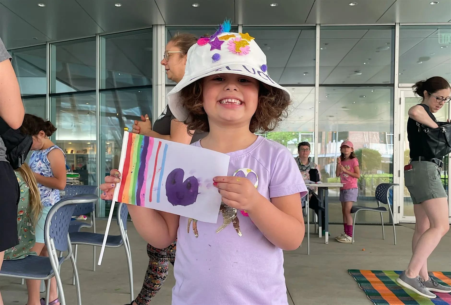 A child holding up an art project they made at the Akron Art Museum